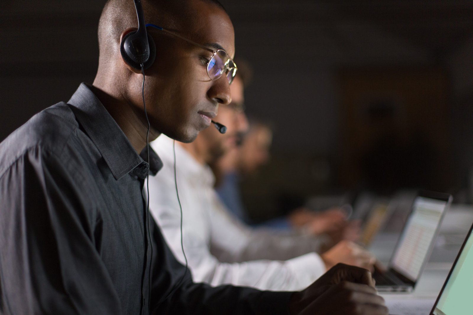 Focused call center operator typing on laptop