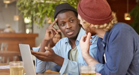Two friends discussing over drinks.